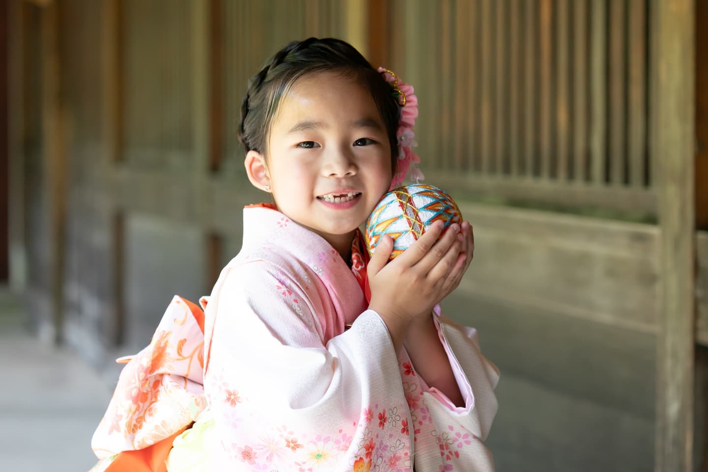 代々木八幡宮の回廊で七五三撮影をしている７歳の着物姿の女の子。鞠を持って笑顔が可愛い写真